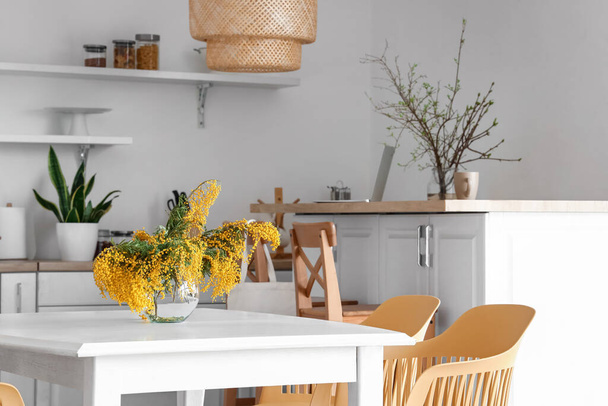 Vaso com flores de mimosa na mesa de jantar na cozinha - Foto, Imagem
