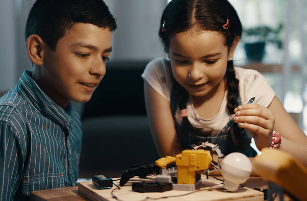 Elle a eu la touche d'un pro. Prise de vue de deux adorables jeunes frères et sœurs construisant un jouet robotique ensemble à la maison. - Photo, image
