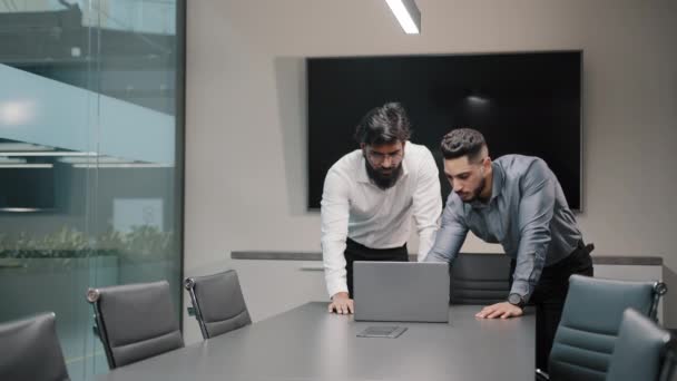 Двое мужчин арабских рабочих менеджеры программисты бизнесмены стоят в офисе, глядя на ноутбук думаю, проблемы связи осложнение работы африканский босс лидер женщины бизнес-женщины тренер прогулки помочь команде - Кадры, видео
