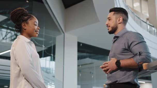 Two happy friendly diverse professionals partners colleagues african female manager businesswoman and male employee businessman talking in office company giving high five success partnership teamwork - Footage, Video