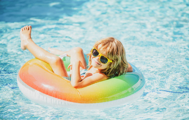 Kids aquapark vacation. Summer weekend. Funny boy in swiming pool on inflatable rubber circle. - Foto, imagen