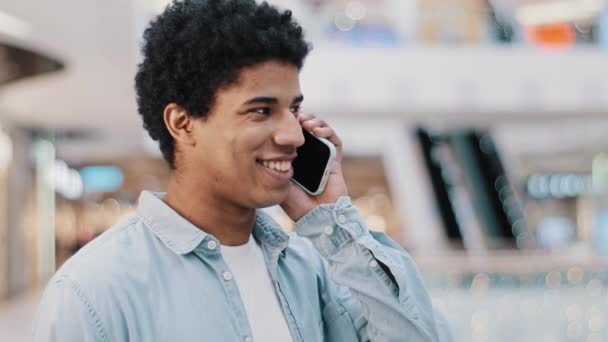 close-up afrikaanse man op zoek naar mobiele telefoon beantwoorden onverwachte oproep praten met vriendin familie glimlachen chatten op mobiele telefoon op afstand vriendelijke praten mobiele verbinding met behulp van smartphone app - Video