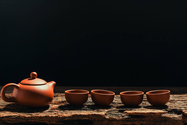 Pitchers and teacups lined up on old wood, black background. - Photo, Image