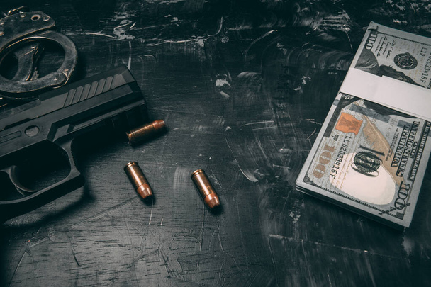 Czarne pistolety, kajdanki, kule, dolary i policyjne radia. Położone na czarnym drewnianym stole. Koncepcja policji korupcyjnej. z przestrzenią coppy - Zdjęcie, obraz