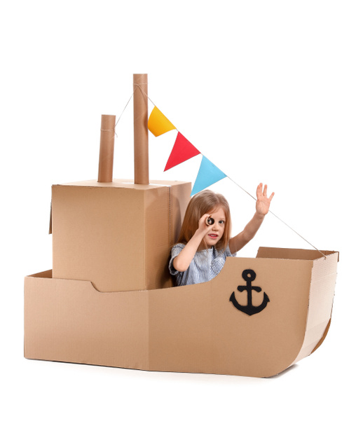 Petite fille mignonne jouant avec le navire en carton sur fond blanc
 - Photo, image