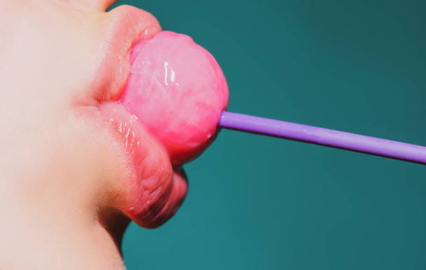 Sexy woman mouth with pink lips holding lollipop, beauty closeup. Sexy girl suck lick lollipop. Beauty glamour concept, close-up. - Foto, afbeelding