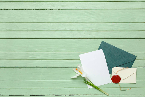 Envelopes with card and flower on green wooden background - Foto, imagen