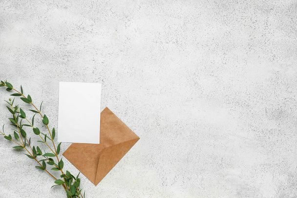Envelope with blank card and eucalyptus branches on light background - 写真・画像