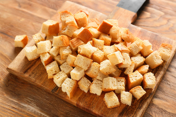 Tábua de corte com croutons saborosos em fundo de madeira, close-up - Foto, Imagem