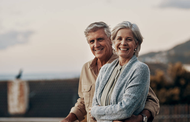 Were happy to be celebrating yet another new year together. Cropped portrait of an affectionate mature couple smiling while standing on a balcony outdoors. - Photo, Image
