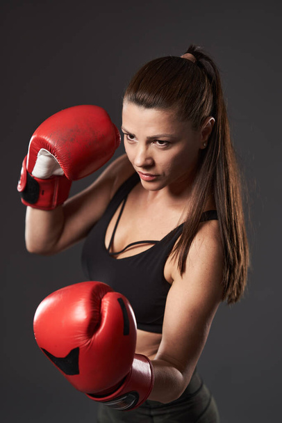 Nainen nyrkkeilijä punaisissa hanskoissa, lyömällä kohokoukulla - Valokuva, kuva