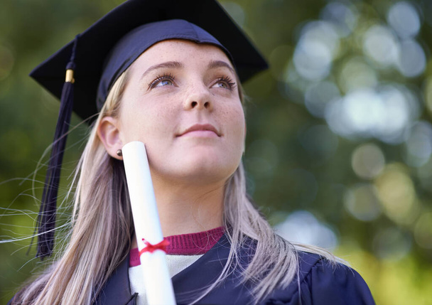 Thinking of her future. A female graduate holding her diploma. - Photo, Image