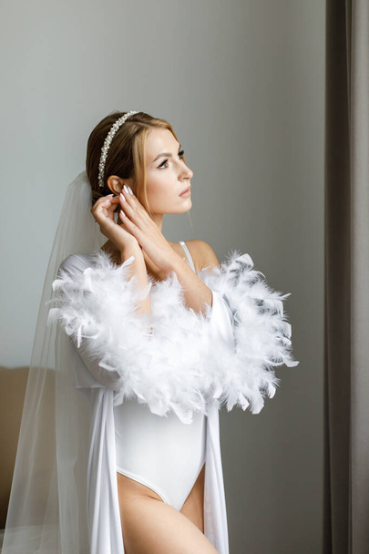 Morning of the bride in a white robe and a veil in the room - Foto, Bild