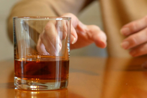 shaking woman hand reaching of glass with whiskey standing on a wooden table, woman's alcoholism problem, concept - Photo, Image