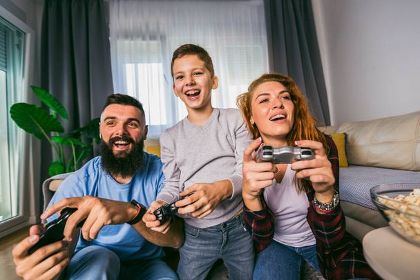 Playful family playing video games together in a living room. - Photo, Image