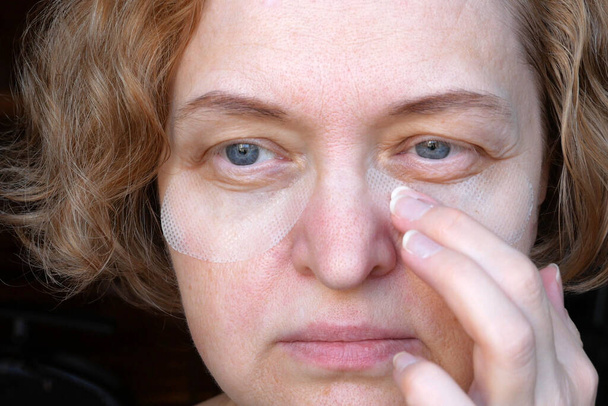 中年の女性の目には目のパッチが付いてる。ポチ症は、上まぶた、怠惰な目の垂れです。美容と顔のコンセプト、最初のしわ、クローズアップ - 写真・画像