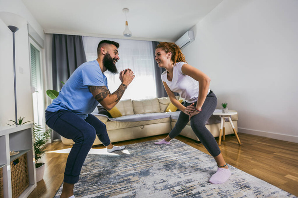 Usmívající se muž a žena doma cvičí. Koncept sportu, fitness, životního stylu a lidí  - Fotografie, Obrázek