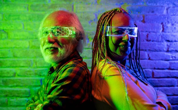 Szczęśliwi starsi przyjaciele zabawiają się futurystycznymi, powiększonymi okularami rzeczywistości, wielorasową parą azjatyckich mężczyzn i latynoską Amerykanką - Metaverse Concept - Zdjęcie, obraz