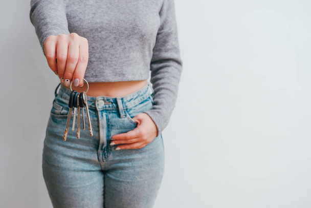 Attractive woman in jeans holding a bunch of keys. Keys near the pocket. Holding in hands house and bunch of keys. - Foto, imagen