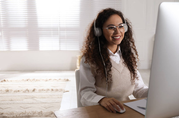 African American woman with headphones using modern computer for studying at home. Distance learning - Foto, Bild