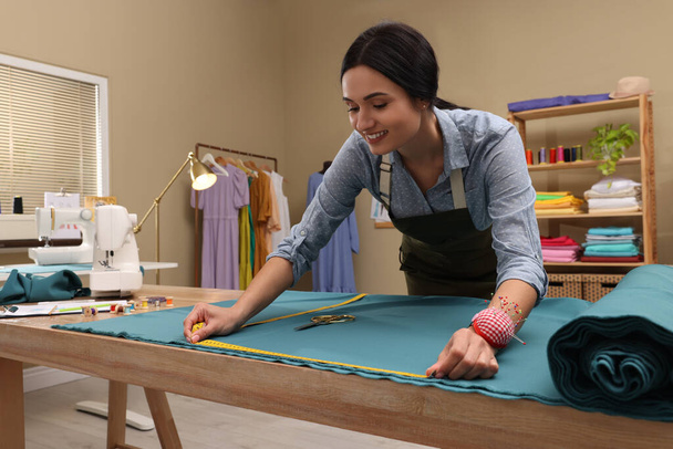 Dressmaker working with light blue fabric in atelier - Zdjęcie, obraz