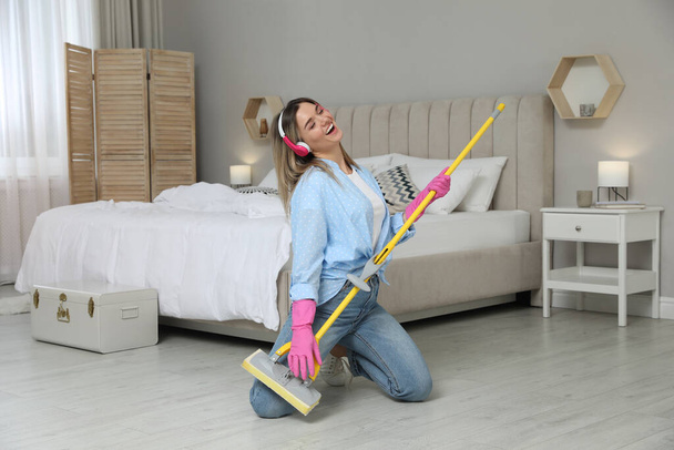 Woman in headphones with mop singing while cleaning at home - Fotoğraf, Görsel