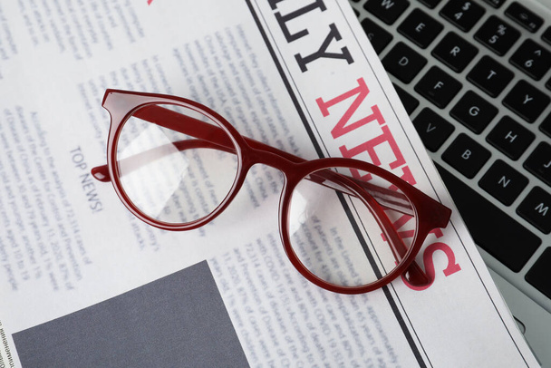 Newspaper and glasses on laptop, top view - Foto, imagen