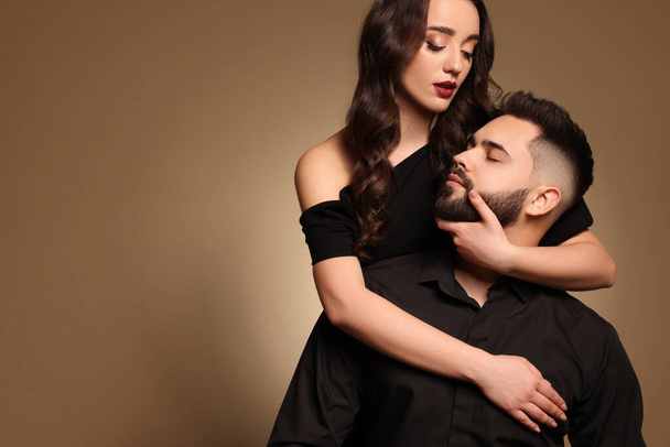 Handsome bearded man with sexy lady on light brown background. Space for text - Fotó, kép