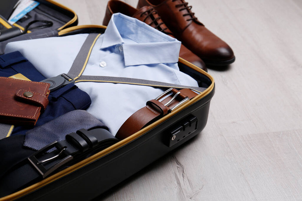 Packed suitcase with business trip stuff on wooden surface. Space for text - Foto, Imagem