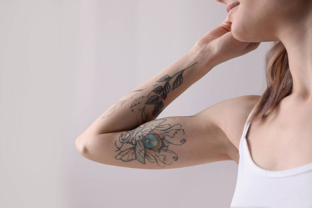 Beautiful woman with tattoos on arm indoors, closeup - Photo, image