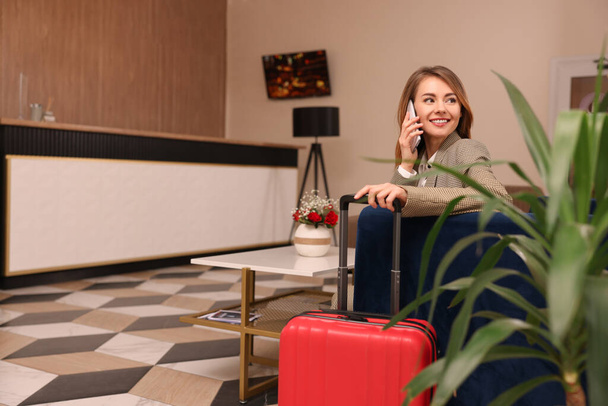 Beautiful woman talking on phone while waiting in hotel hall - Valokuva, kuva