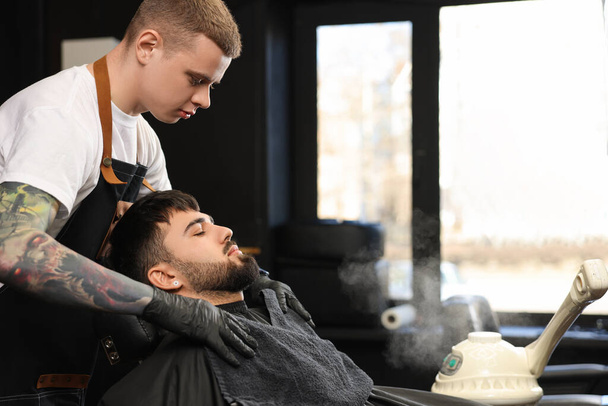Professional hairdresser working with bearded client in barbershop - Foto, Bild