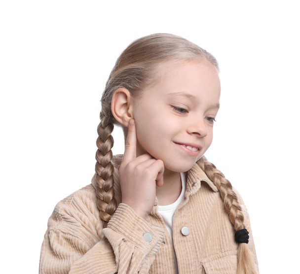 Cute little girl pointing at her ear on white background - Foto, Imagen