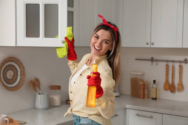 Woman with spray bottle and rag singing while cleaning at home - Foto, immagini