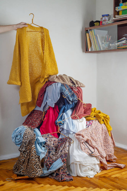 Hand throws clothes into a pile with used clothes. The concept of sustainable fashion. Pile of used clothes on a light background. Second hand for recycling - Fotó, kép