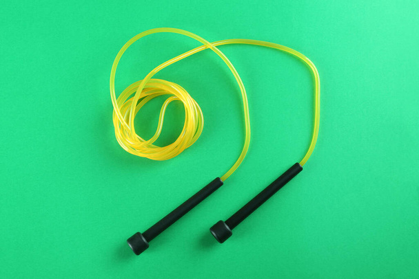 Skipping rope on green background, top view. Sports equipment - Foto, Imagen