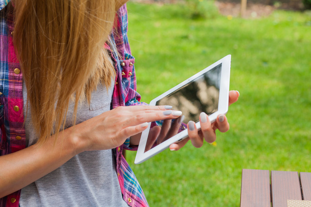 Vrouw zitten in park en de tablet pc gebruiken - Foto, afbeelding