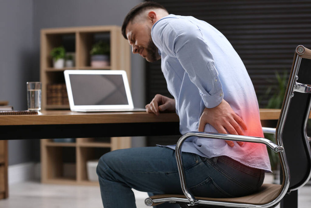 Muž trpící bolestí zad při práci s laptopem v kanceláři. Symptom špatného držení těla - Fotografie, Obrázek