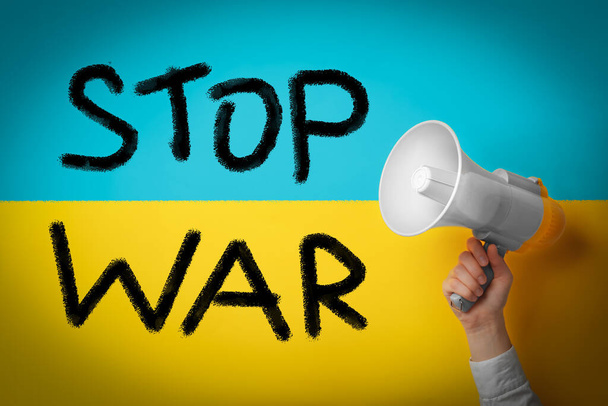 Stop war in Ukraine. Woman with megaphone against Ukrainian national flag - Fotó, kép