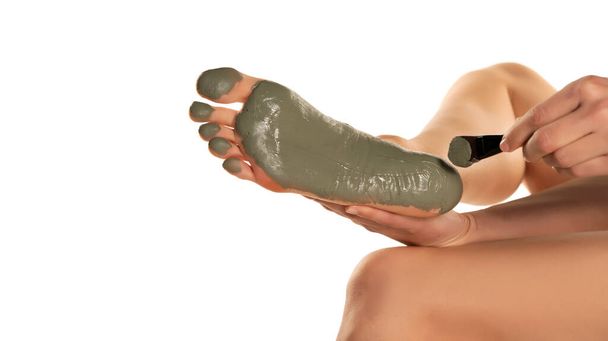 жінка наносить зелену грязьову маску на ногу на білому тлі
 - Фото, зображення