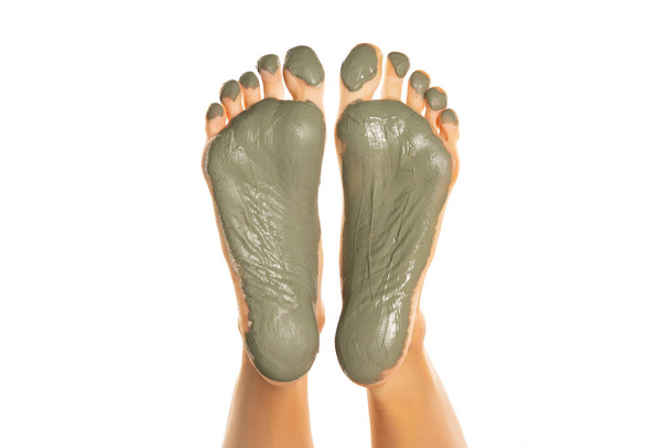 pies femeninos con máscara de barro verde sobre un fondo blanco - Foto, imagen