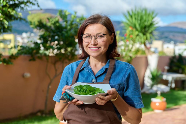 Retrato ao ar livre de cozinheiro feminino sorridente em um avental com placa de hortelã fresca - Foto, Imagem
