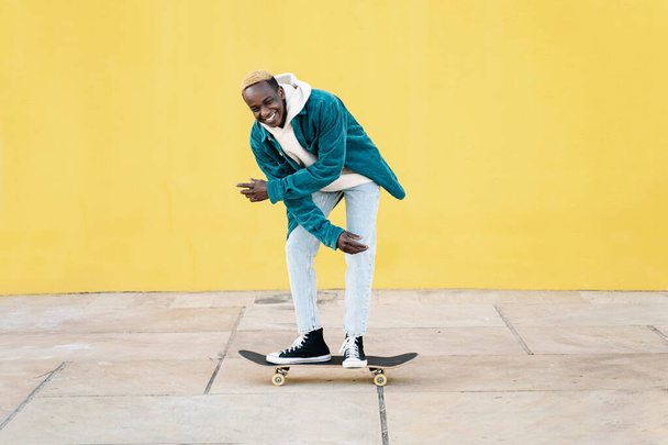 Funny black man enjoying riding a skateboard. Concept of happiness and satisfaction - Photo, Image
