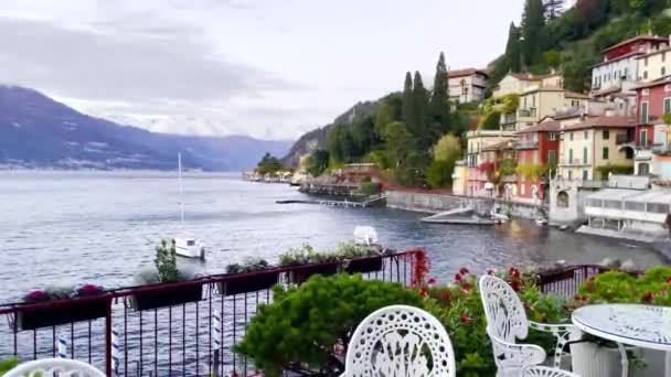 Widok z kawiarni na świeżym powietrzu do pięknego krajobrazu jeziora Como z pływającym jachtem na wodzie, miasto i pokryte śniegiem szczyty Alp. - Materiał filmowy, wideo