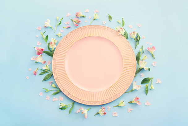 Top view of vintage white empty plate over spring flowers. Flat lay - Zdjęcie, obraz