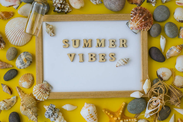 Composition sheet white paper text SUMMER VIBES, seashells, pebbles, mockup on yellow background. Blank, top view, still life, flat lay. sea vacation travel concept tourism and resorts. Summer holidays - Foto, Bild