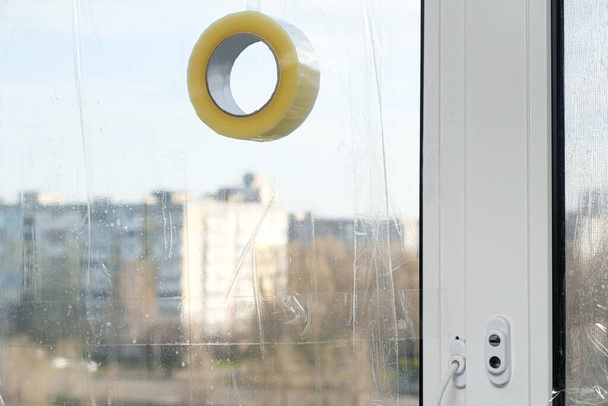 Sigillare le finestre con nastro adesivo durante la guerra in Ucraina per prevenire la formazione di molti frammenti durante l'onda d'urto - Foto, immagini