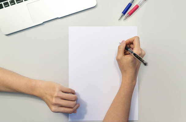 Donne mano tenuta penna scrittura su sfondo bianco carta a5. - Foto, immagini