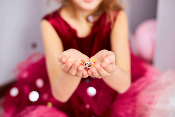 Beautiful little girl blows up multicolored confetti, having fun at home birthday party. Happy birthday child. - Φωτογραφία, εικόνα
