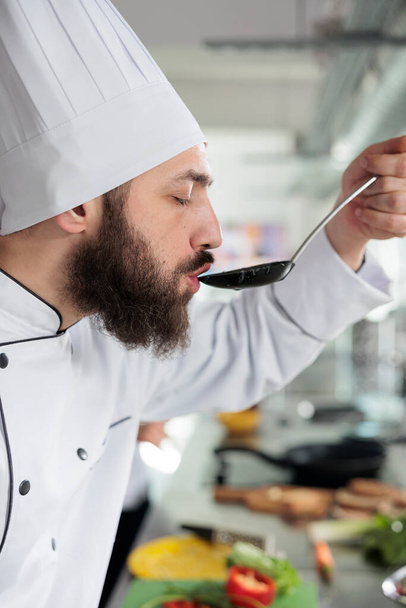 Head chef tasting delicious gourmet dish cooked in professional kitchen and served at dinner service in fine dining restaurant. - Φωτογραφία, εικόνα
